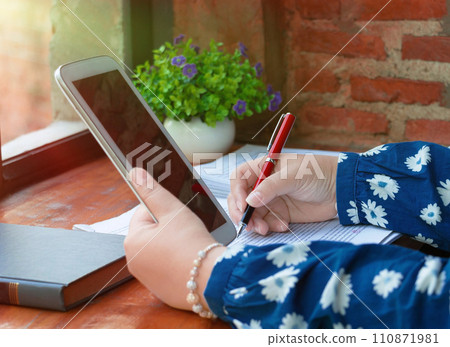 hand holding red pen over blurred paperwork for proofreading hand holding red pen over blurred paperwork for proofreading 110871981