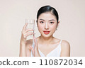 beautiful young asian woman holding glass of clear water near face 110872034