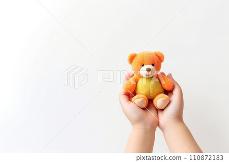 AI generated Child hands holding smiling cute little teddy bear on white background with copy space. 110872183