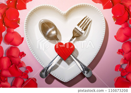 Heart plate with silverware of spoon and fork with a red heart and rose petal 110873208