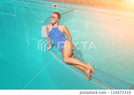 Bikini-clad woman enjoys poolside relaxation. Poolside ambiance. Capturing woman's relaxed time near pool. Bikini-clad woman enjoys poolside relaxation. Poolside ambiance. Capturing woman's relaxed time near pool. 110873319