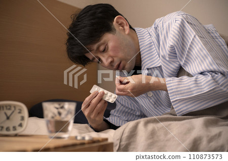 Man taking medicine before bed, insomnia, sleeping pills 110873573