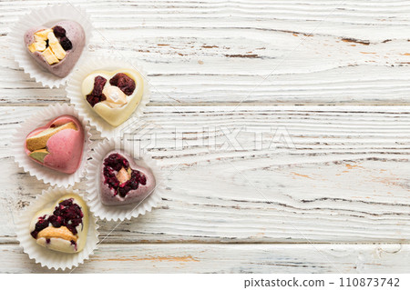 chocolate sweets in the form of a heart with fruits and nuts on a colored background. top view with space for text, holiday concept 110873742