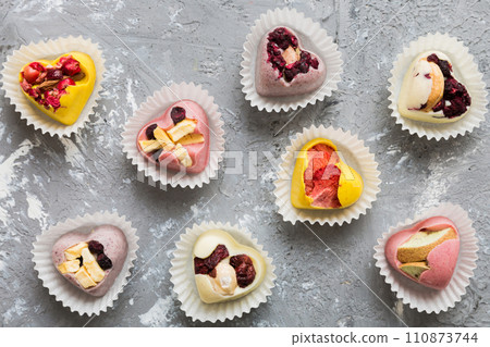 chocolate sweets in the form of a heart with fruits and nuts on a colored background. top view with space for text, holiday concept 110873744
