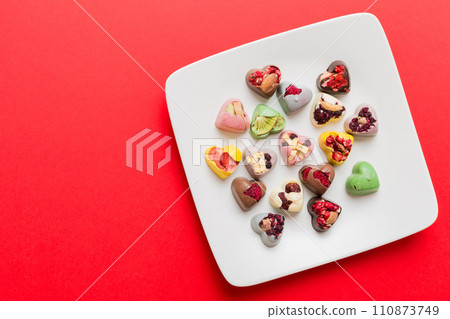Plate with different chocolate on colored background. Assortment of fine chocolates top view vith copy space Health and obesity concept 110873749