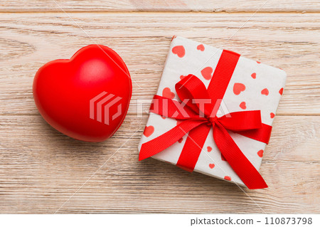 gift box with red bow and red heart on colored background . Top view. Flat lay gift box with red bow and red heart on colored background . Top view. Flat lay 110873798