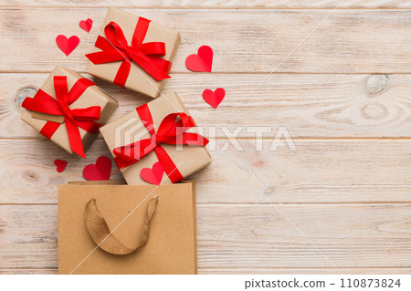 Gift boxes pop out from paper bag top view on colored background. bag packing handmade boxes fall out Concept of holidays, shopping, sale, discounts. Top view, flat lay Gift boxes pop out from paper bag top view on colored background. bag packing handmade boxes fall out Concept of holidays, shopping, sale, discounts. Top view, flat lay 110873824