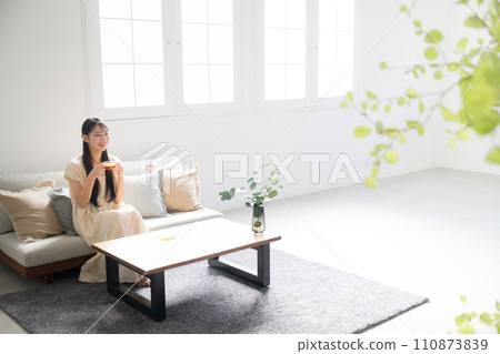 A woman with long hair relaxing in her room, drinking coffee or tea and relaxing A woman with long hair relaxing in her room, drinking coffee or tea and relaxing 110873839