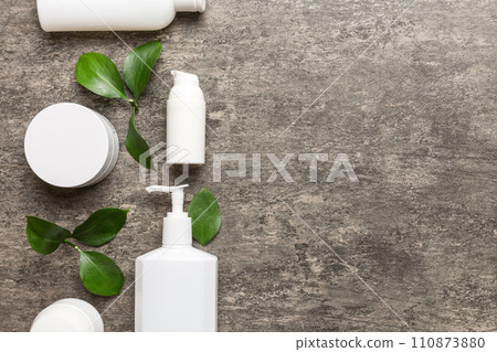 Organic cosmetic products with green leaves on cement background. Copy space, flat lay Organic cosmetic products with green leaves on cement background. Copy space, flat lay 110873880