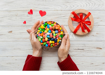 Female hands with delicious candies in box on color background Female hands with delicious candies in box on color background 110874044