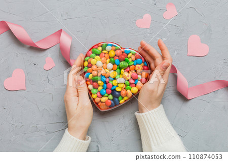 Female hands with delicious candies in box on color background 110874053