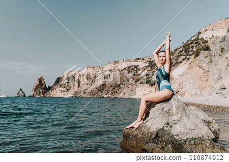 Woman beach vacation photo. A happy tourist in a blue bikini enjoying the scenic view of the sea and volcanic mountains while taking pictures to capture the memories of her travel adventure. 110874912
