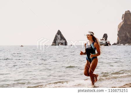 Woman beach vacation photo. A happy tourist in a blue bikini enjoying the scenic view of the sea and volcanic mountains while taking pictures to capture the memories of her travel adventure. 110875251