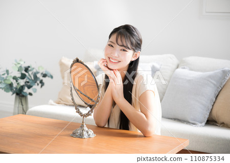 Asian (Japanese) smiling woman checking her skin in the mirror 110875334