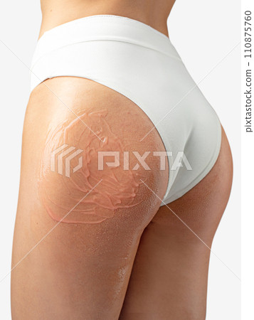 Pink care lotion applied on young woman buttock 110875760