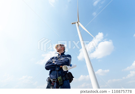 Professional technician worker man stand with arm-crossed and stand in front of wind turbine or windmill with blue sky in concept of green energy for good environment. 110875778