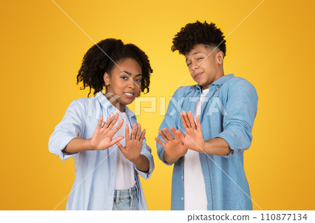 A cheerful young woman and man stand back to back against a vibrant yellow background A cheerful young woman and man stand back to back against a vibrant yellow background 110877134