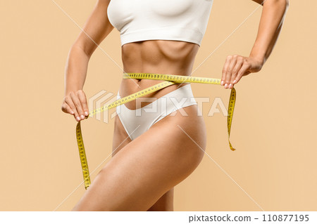 Body Sculpting. Fit woman in underwear measuring her waistline with measure tape 110877195