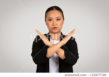 Assertive Asian businesswoman in a black suit making a strong 'no' gesture with her arms crossed Assertive Asian businesswoman in a black suit making a strong 'no' gesture with her arms crossed 110877196