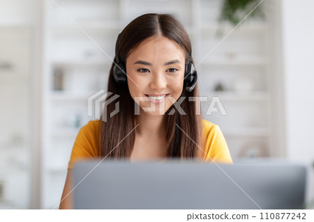 Telecommuting Concept. Beautiful Asian Female Wearing Headset Working On Laptop At Home 110877242