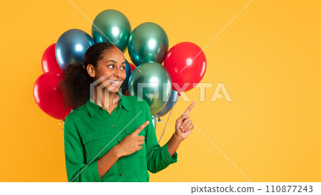 black teen girl pointing aside posing with colorful balloons, studio black teen girl pointing aside posing with colorful balloons, studio 110877243