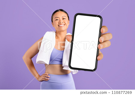 Happy asian woman with towel shows smartphone blank screen 110877269