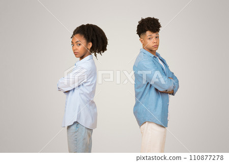 A young African American woman and man stand back-to-back with crossed arms A young African American woman and man stand back-to-back with crossed arms 110877278