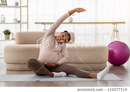 Cheerful pregnant young black woman exercising at home 110877314