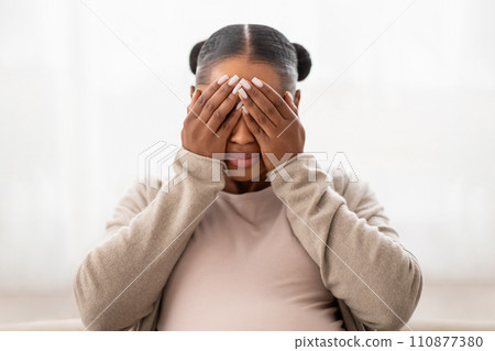 Closeup of african american pregnant lady crying at home Closeup of african american pregnant lady crying at home 110877380