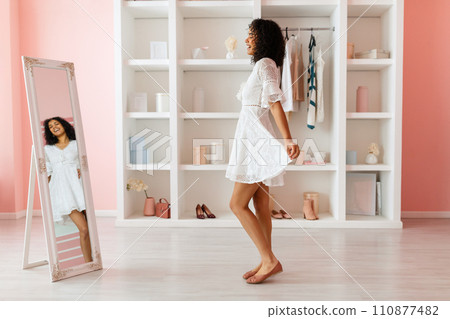 Joyful woman twirling in a white lace dress 110877482