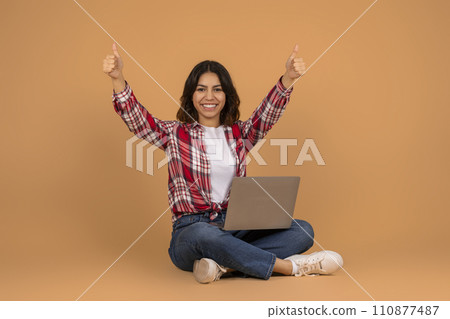Happy arab woman with laptop showing thumb ups Happy arab woman with laptop showing thumb ups 110877487