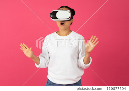 Surprised young asian woman wearing virtual reality headset and gesturing with excitement Surprised young asian woman wearing virtual reality headset and gesturing with excitement 110877504