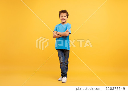 Confident latin boy with arms crossed in blue shirt, yellow background Confident latin boy with arms crossed in blue shirt, yellow background 110877549