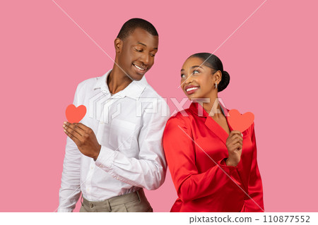 Black couple holding red hearts, man in white, woman in red, playful affection 110877552