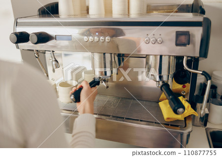 Close up of female barista making coffee in a coffee machine while working in cafe Close up of female barista making coffee in a coffee machine while working in cafe 110877755