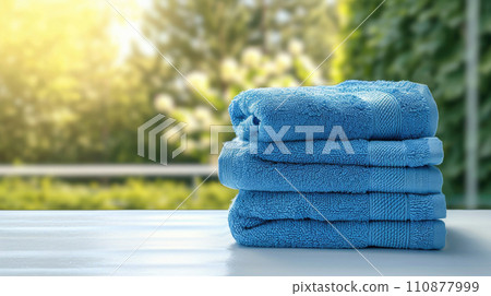 Stack of blue towels on the table with garden view Stack of blue towels on the table with garden view 110877999