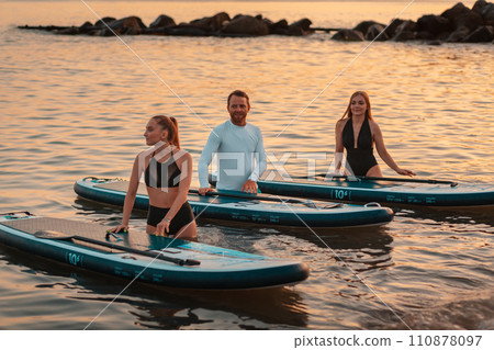 Instructor teaches women to swim on a sup boards. Group of caucasian people surfing at the ocean. Summer sport and recreation Instructor teaches women to swim on a sup boards. Group of caucasian people surfing at the ocean. Summer sport and recreation 110878097