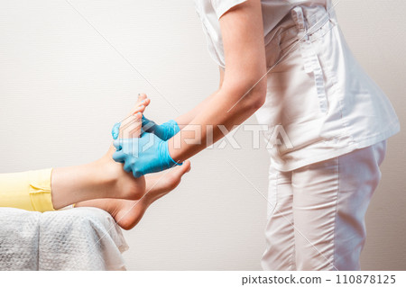 A podologist massages the feet of client. Close-up of the legs and master's hands. Copy space. The concept of pedicure and chiropody A podologist massages the feet of client. Close-up of the legs and master's hands. Copy space. The concept of pedicure and chiropody 110878125