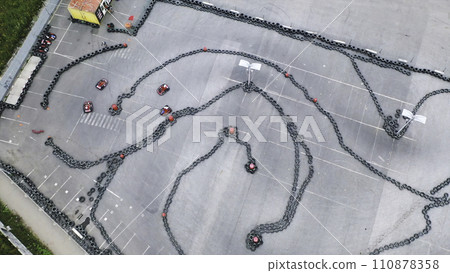 Aerial view of the karts pilots traning or competing on the karting trace in protective uniform and helmet. Media. Kart driving training. Kart racing Aerial view of the karts pilots traning or competing on the karting trace in protective uniform and helmet. Media. Kart driving training. Kart racing 110878358