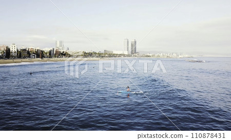 The surfer rides and swims on the board dissecting the waves of the ocean. Stock. Top view of a man riding on a Board on the waves The surfer rides and swims on the board dissecting the waves of the ocean. Stock. Top view of a man riding on a Board on the waves 110878431