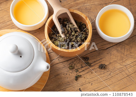 Tea leaves in wood bowl with tea cups on wooden table, copy space 110878543