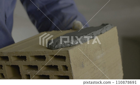 Construction of brick wall. Trowel spreading cement on bricks. Worker spreads cement for bricks Construction of brick wall. Trowel spreading cement on bricks. Worker spreads cement for bricks 110878691