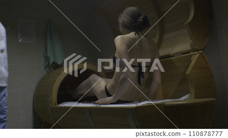 The woman taking spa treatments. Girl sitting in a pine barrel 110878777
