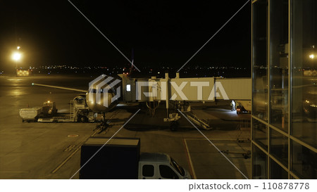 Close view of aircraft fuselage near the entering baggage door, at night. Plane takes passengers. Timelapse 110878778