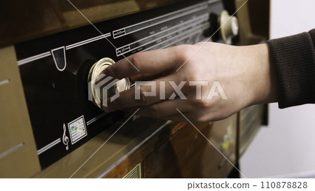 Close-up of man's hand rotating the knob on the old radio. Concept. Vintage technology 110878828