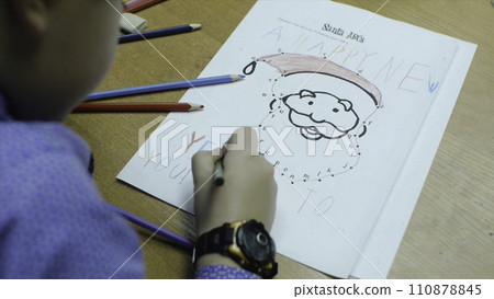 High angle view of boy drawing with color pencil on paper at desk in classroom. Clip. A cute little boy drawing with a pencil close up High angle view of boy drawing with color pencil on paper at desk in classroom. Clip. A cute little boy drawing with a pencil close up 110878845