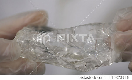 Scientist holding sample of raw crystal in hands. Male hand holding a fragment of rock crystal mineral 110878916