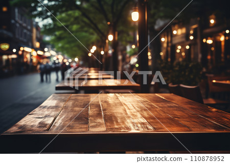 Evening at outdoor cafe with empty wooden tables and glowing street lights, creating cozy atmosphere 110878952