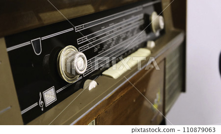 Close-up of man's hand rotating the knob on the old radio. Concept. Vintage technology 110879063