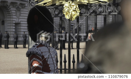 Close-up view of the royal guard soldier in traditional uniform standing near the gate into Buckingham Palace, London, Great Britain. Action. Detail of Queen's Soldier Close-up view of the royal guard soldier in traditional uniform standing near the gate into Buckingham Palace, London, Great Britain. Action. Detail of Queen's Soldier 110879076